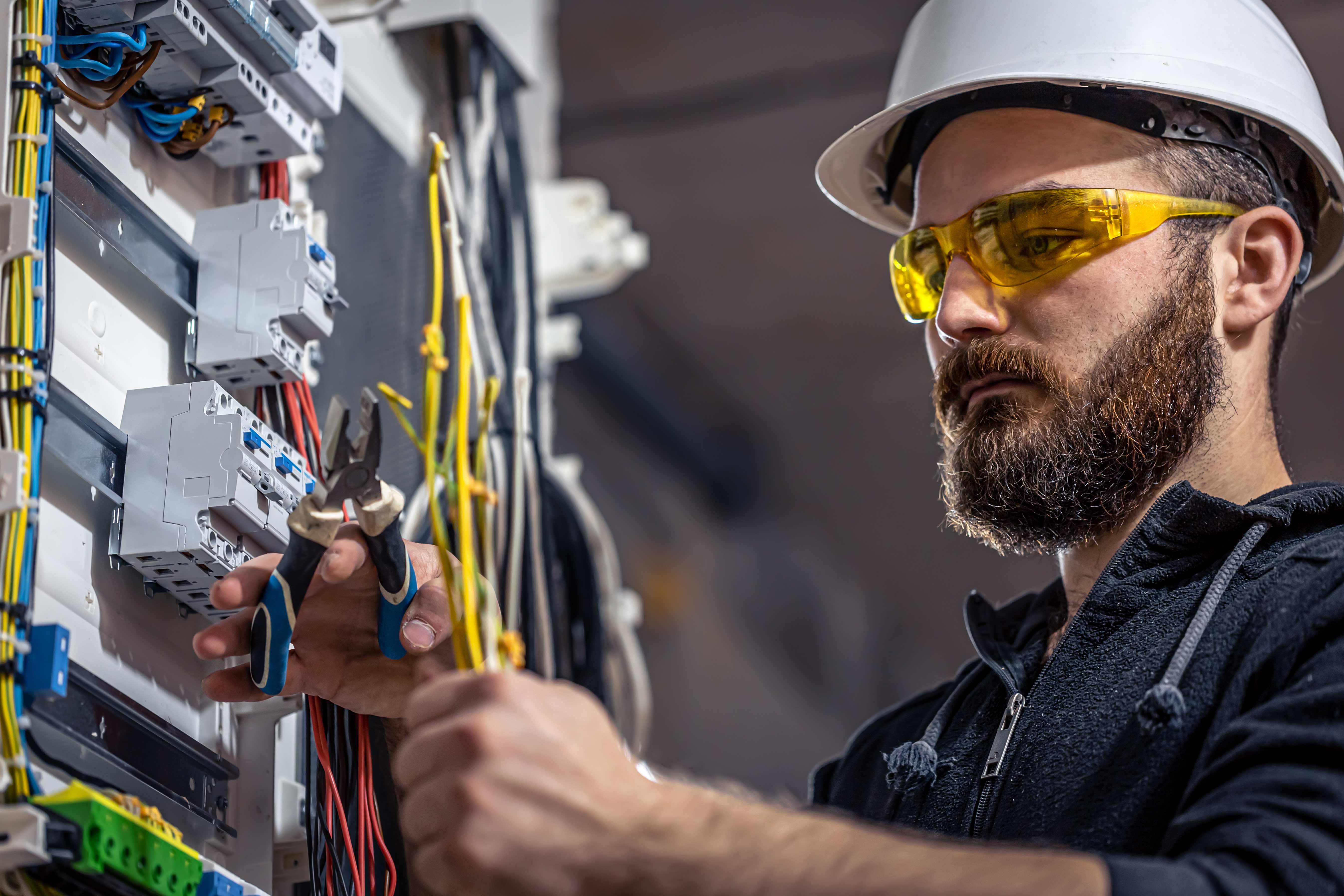 Male electrician at the checkout counter on a blurred background of a switchboard