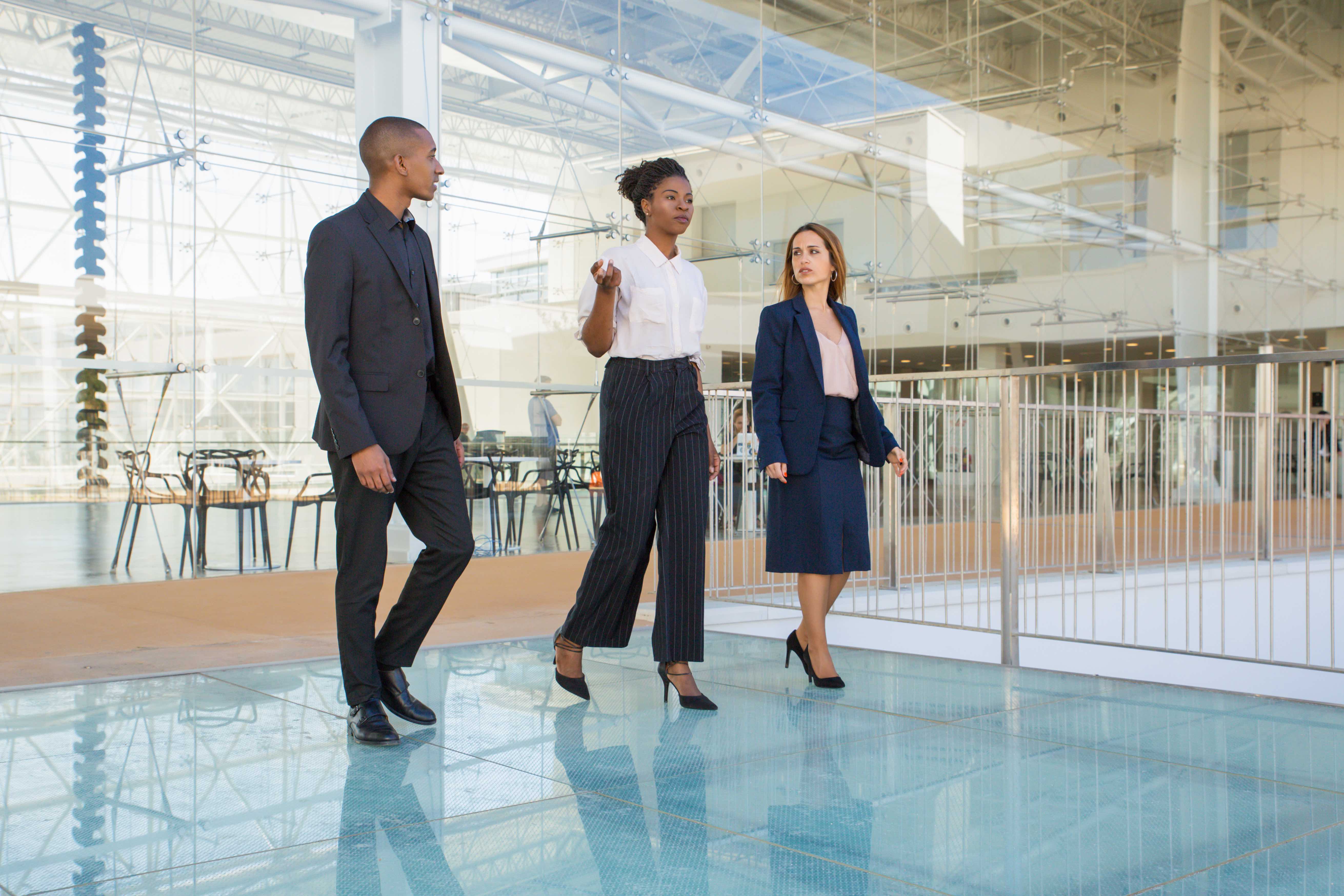 Business team of three walking through office hallway and talking.