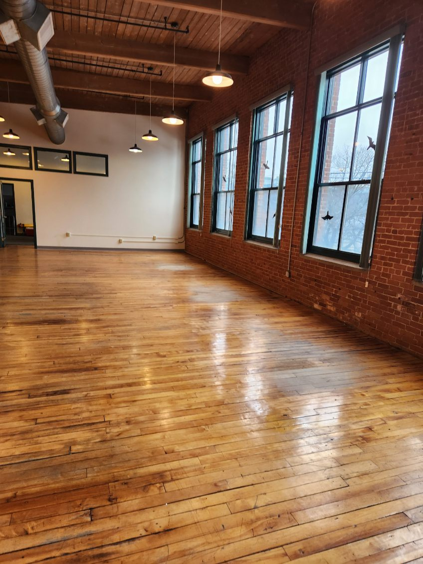 Cleared open office area with existing windows, brick walls and wood flooring retained