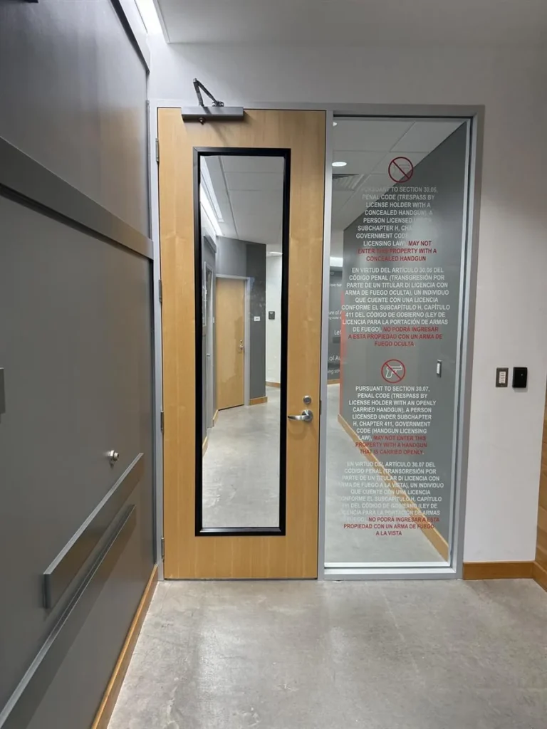 Completed secured elevator lobby entry with glazed panel, access control keypad, wood door, and retained finishes