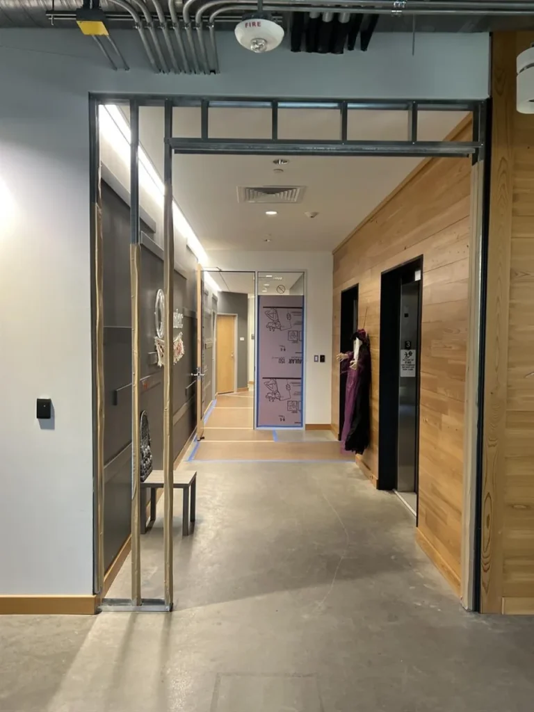 New metal framing for the secured elevator lobby beside Stantec's retained wood wall in Austin